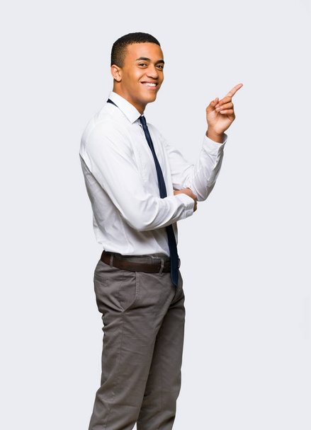 Young afro american businessman pointing finger to the side in lateral position on isolated background - Фото, зображення