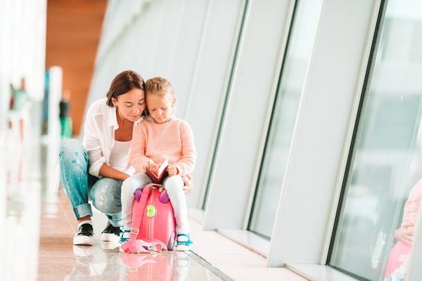 Onnellinen perhe lentokentällä istuu matkalaukku tarkastuskortilla odottaa lennolle
 - Valokuva, kuva