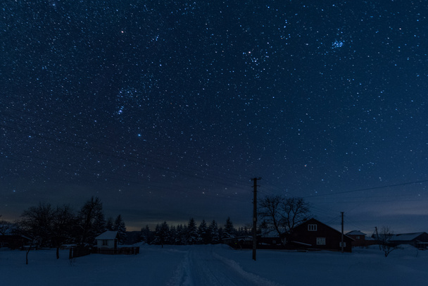 starry night sky above village covered with snow in carpathian mountains - Fotografie, Obrázek