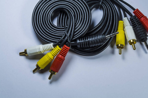 Twee hanks van kabels met multi-gekleurde stekkers een tulp. Zwarte koord. Witte monofone achtergrond. - Foto, afbeelding