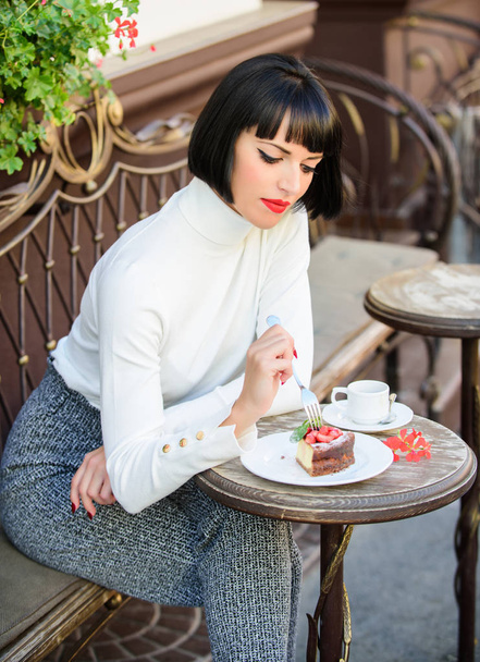 Pleasant time and relaxation. Gourmet concept. Delicious gourmet cake. Woman attractive brunette eat gourmet cake cafe terrace background. Gastronomical enjoyment. Girl relax cafe with cake dessert - Photo, image
