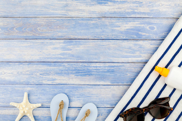 kreatives flaches Lagekonzept für Sommerreisen. Draufsicht auf Strandtuch Sonnenbrille Muscheln Seesterne auf pastellblauen Holzplanken Hintergrund mit Kopie Raum Attrappe Vorlage für Text - Foto, Bild