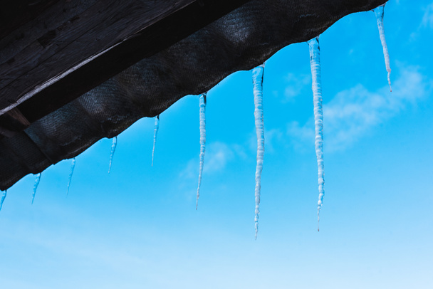 sharp icicles on roof against clear blue sky - Photo, Image