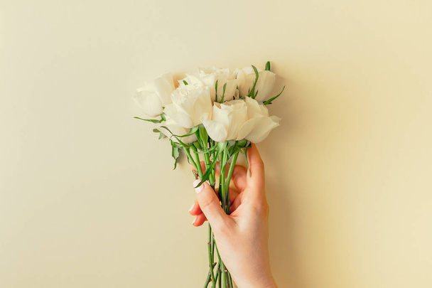 Creative top view flat lay woman hands holding fresh white roses bouquet with copy space pastel paper background minimalism style. Template feminine blog social media holiday wedding invitation card - 写真・画像