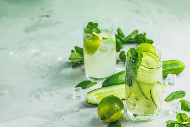 Detox cocktail of mint, cucumber and lemon and mojito cocktail with lime and mint in highball glasses on a gray concrete stone surface background. With copy space for your text - Fotoğraf, Görsel