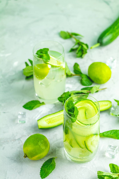 Detox cocktail of mint, cucumber and lemon and mojito cocktail with lime and mint in highball glasses on a gray concrete stone surface background. With copy space for your text - Foto, immagini
