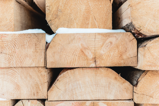 troncos de corte de madeira marrom empilhados em pilha e cobertos com neve
 - Foto, Imagem
