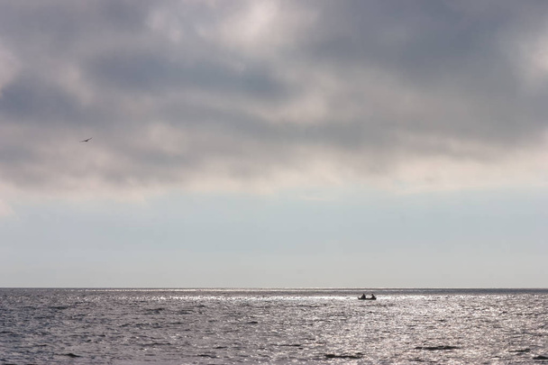 Two people in a boat on the horizon at sea - 写真・画像