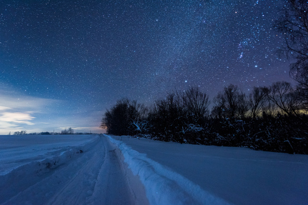 cielo oscuro estrellado y carretera nevada en las montañas de los Cárpatos por la noche en invierno
 - Foto, Imagen