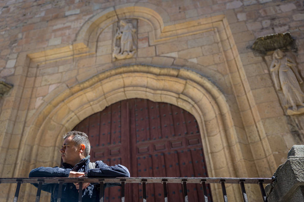Tourist leaning on a railing in front of an old church in the city of Segovia, Spain - Photo, Image
