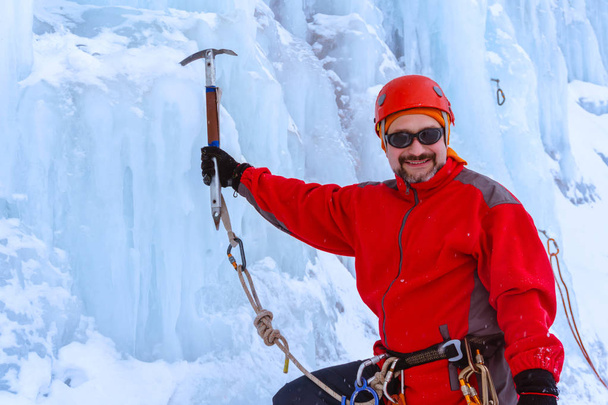 smiling bearded mountaineer with ice ax on blue glacier background - Photo, Image