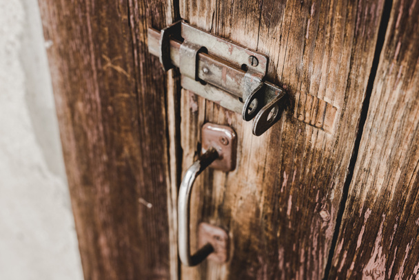 Close up van houten verweerde deur met roestige handvat en vergrendelen - Foto, afbeelding