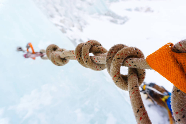 Ancoraggio arrampicata su ghiaccio con vite di ghiaccio, moschettoni e corda di sicurezza, concentrandosi su nodi di corda, primo piano
 - Foto, immagini