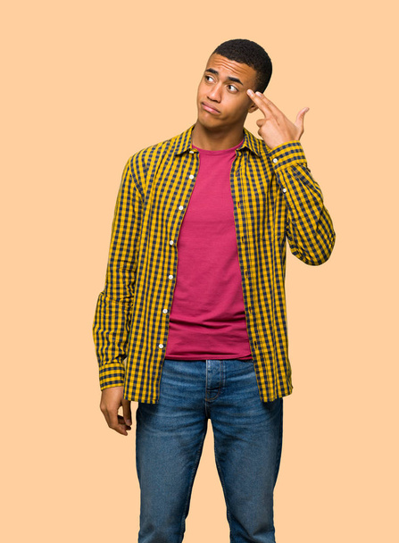Jonge afro-Amerikaanse man met problemen zelfmoord gebaar maken op geïsoleerde achtergrond - Foto, afbeelding