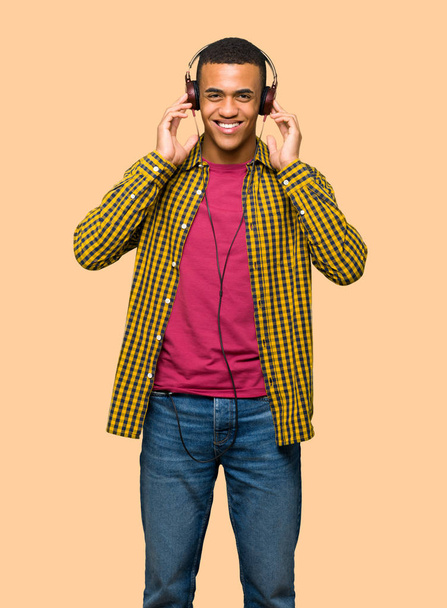 Молодой афро-американец слушает музыку в наушниках на изолированном фоне
 - Фото, изображение