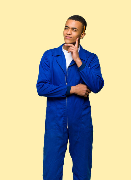 Jonge afro Amerikaanse arbeider man denken een idee tijdens het opzoeken op geïsoleerde achtergrond - Foto, afbeelding