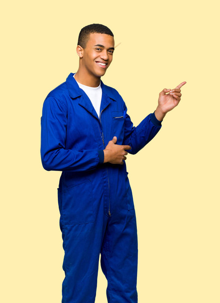 Nuori afro amerikkalainen työntekijä mies osoittaa sormella sivulle sivuttain eristetty tausta
 - Valokuva, kuva