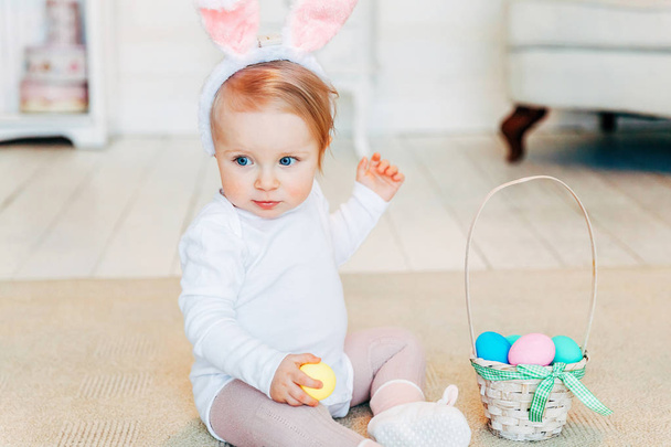 Little child girl wearing bunny ears on Easter day and playing with painted eggs - Photo, Image