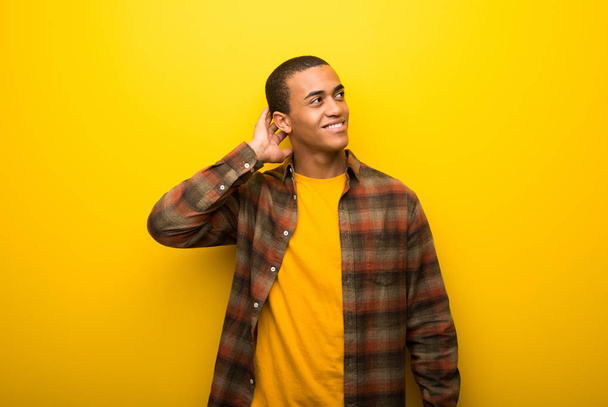 Giovane uomo afroamericano su uno sfondo giallo vibrante pensando a un'idea mentre gratta la testa
 - Foto, immagini