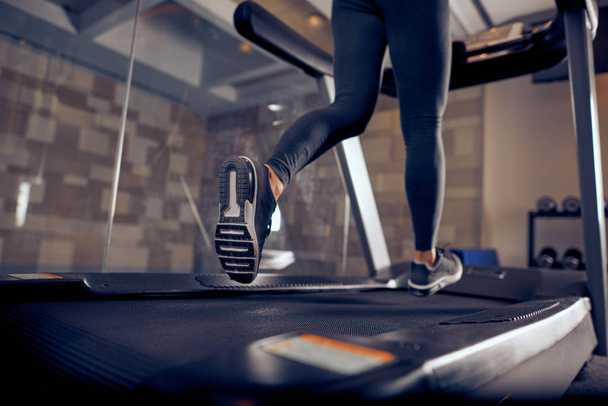 Κοντινό πλάνο της τα πόδια της γυναίκας που τρέχει στο διάδρομο. Εσωτερικό γυμναστήριο. - Φωτογραφία, εικόνα