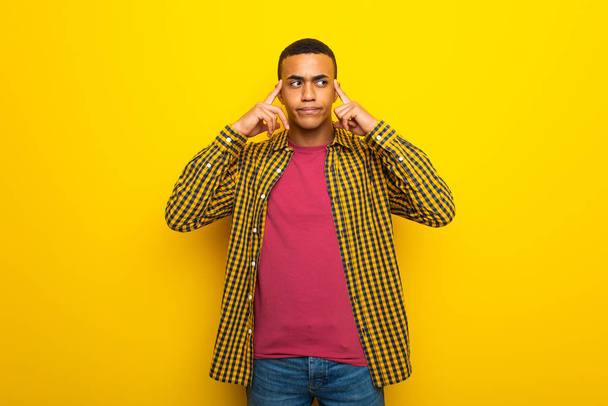 Nuori afro amerikkalainen mies keltaisella taustalla, jolla on epäilyksiä ja ajattelua
 - Valokuva, kuva