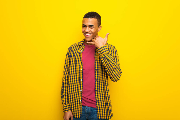 Jeune homme afro-américain sur fond jaune faisant un geste téléphonique. Rappelle-moi signe
 - Photo, image
