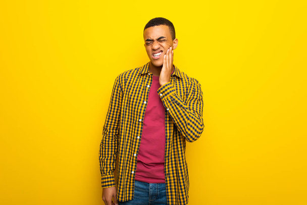 Young afro american man on yellow background with toothache - Foto, Imagen