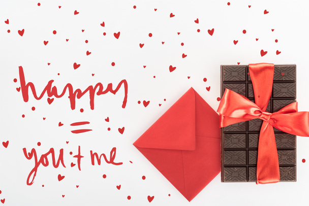 view from above of envelope and delicious chocolate wrapped by festive ribbon isolated on white, st valentine day concept with love lettering - Photo, image