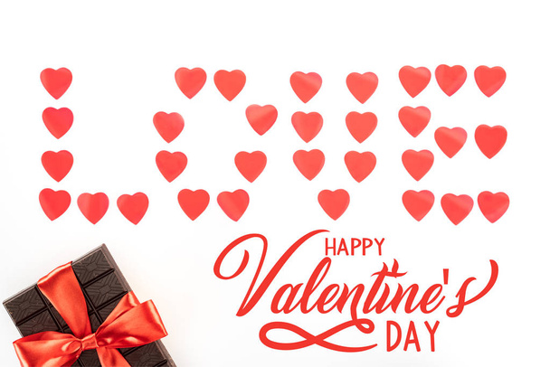 vlakke leggen met liefde gemaakt van hart symbolen en chocolade verpakt door feestelijk lint geïsoleerd op witte, happy Valentijnsdag met "love" belettering belettering - Foto, afbeelding