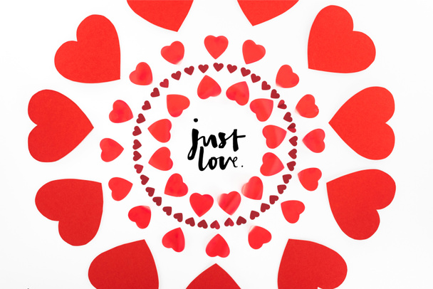 erhöhte Ansicht von Kreisen aus roten Herzsymbolen isoliert auf weißem, Valentinstag-Konzept mit "Just Love" -Schriftzug - Foto, Bild
