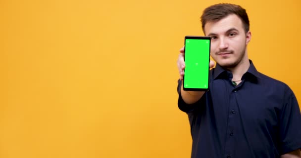 Young man holds a phone with green screen in hands - Séquence, vidéo