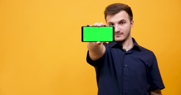 Man points a smartphone with green screen on it - Séquence, vidéo