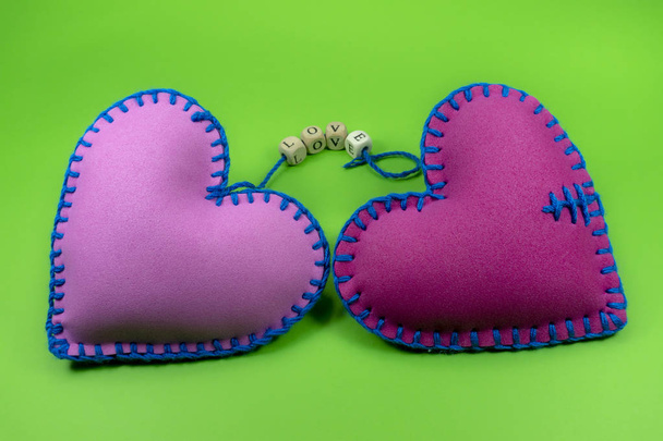 El Tekstil kalpler kelime aşk romantik ilişki, Sevgililer günü, kırık kalp ve kavram için yeşil chromakey arka plan üzerinde dizelerde dişli bloklar ile dikişli - Fotoğraf, Görsel