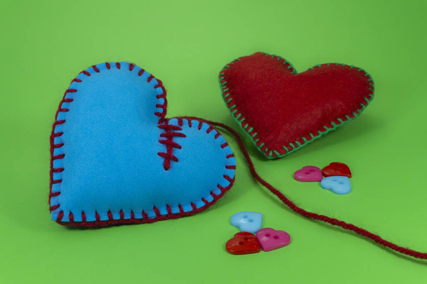 herzförmige handgenähte Textilherzen aus rosa Stoff und mit blauen Fäden auf grünem Chromakey-Hintergrund genäht für romantische oder valentine Konzepte - Foto, Bild