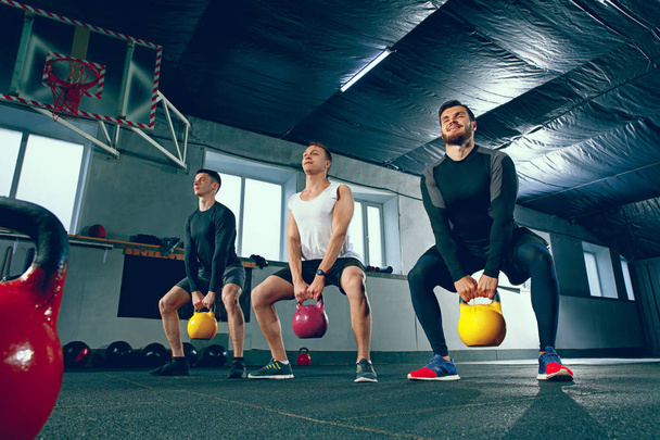 Los jóvenes fuertes de fitness en ropa deportiva haciendo ejercicios en el gimnasio
 - Foto, imagen