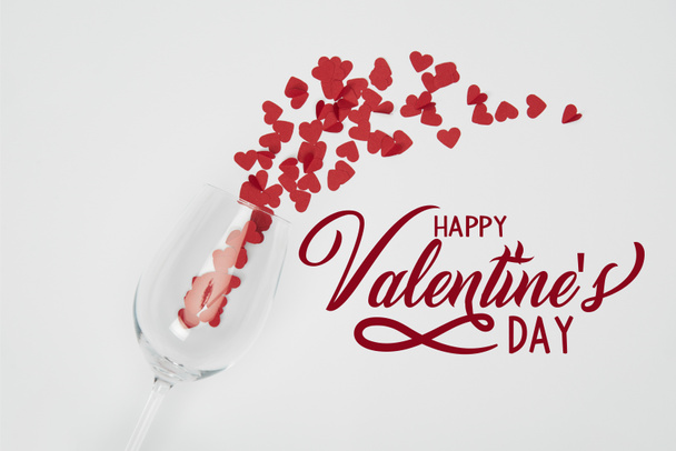 vista dall'alto del bicchiere di vino e piccoli cuori di carta tagliati su sfondo bianco con scritte "Happy San Valentino"
  - Foto, immagini