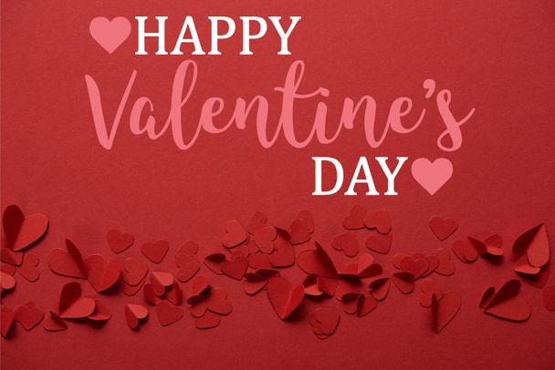 pile of decorative paper cut hearts on red background with "Happy valentines day" lettering  - Photo, image