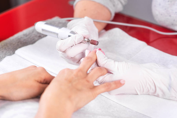 Processo de manicure profissional, limpando as unhas com um cortador de manicure, no salão beutician
. - Foto, Imagem