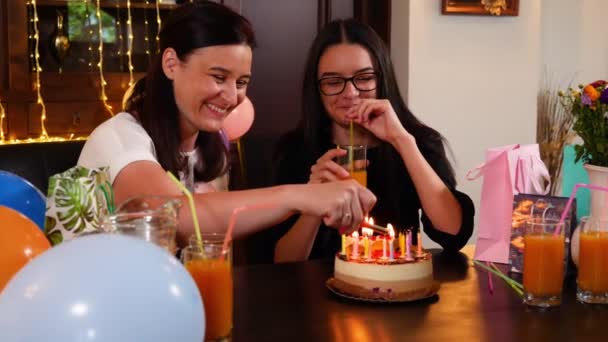 Счастливые девочка-подросток и мама с тортом на день рождения на юбилейной вечеринке. Зажигание свечей на праздничном торте. Люди празднуют день рождения. Медленное движение 4k рукоятка
 - Кадры, видео