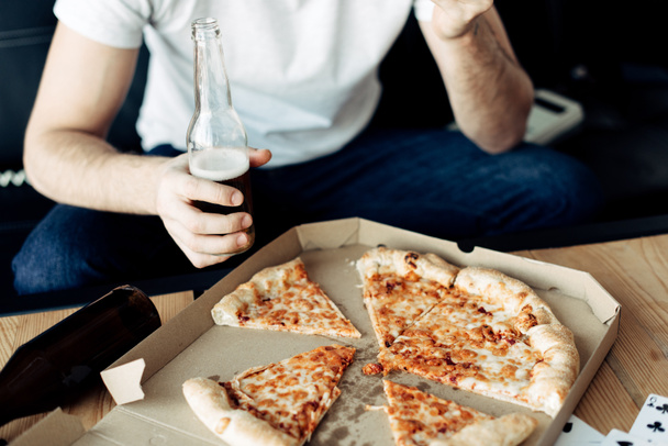 cropped view of man holding bottle near tasty pizza - 写真・画像