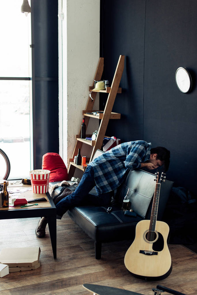 drunk man feeling nauseated after party in messy living room - 写真・画像