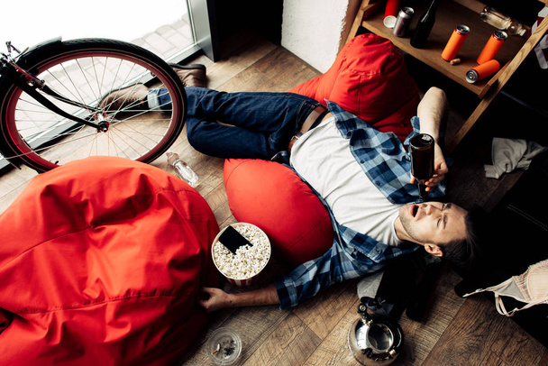 drunk man lying on bean bag and drinking beer  - Фото, изображение