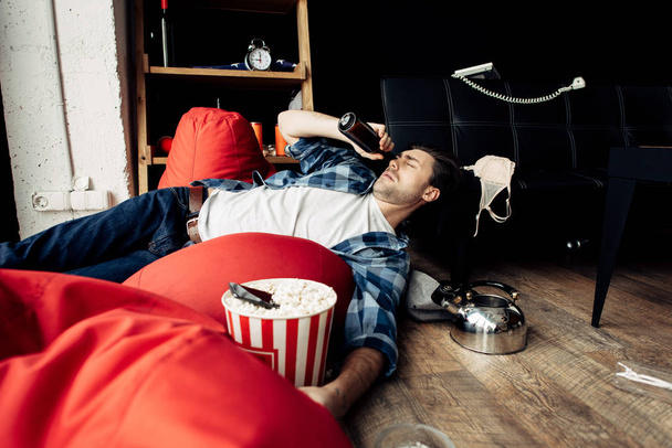 sleepy drunk man lying on bean bag and drinking beer  - 写真・画像