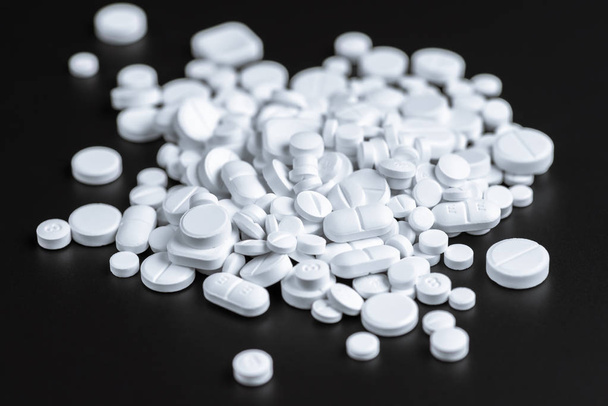 Белые таблетки или капсулы на черном фоне с копировальным пространством
. - Фото, изображение