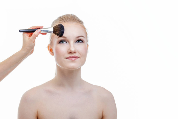 Maquillaje artista aplicando polvo para hermosa mujer joven sobre fondo blanco
 - Foto, Imagen