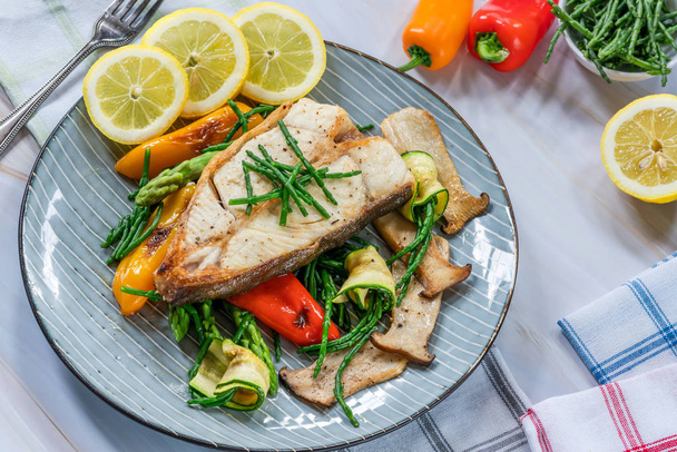Grilled halibut steak with vegetables - sweet mini peppers, courgette, asparagus and oyster mushrooms, garnished with samphire - Fotografie, Obrázek