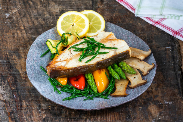 Grilled halibut steak with vegetables - sweet mini peppers, courgette, asparagus and oyster mushrooms, garnished with samphire - Foto, Imagen