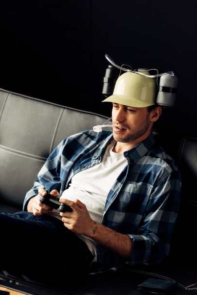 красивый мужчина, пьющий из пивного шлема и играющий в видеоигры
 - Фото, изображение