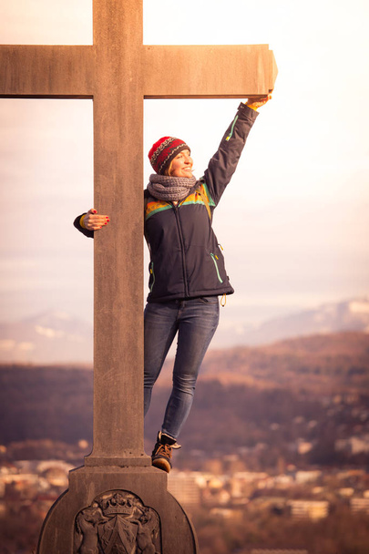 Young girl stands proud and happy on a summit cross, autumn - Foto, Bild
