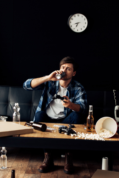 мужчина пьет пиво и играет в видеоигры дома
 - Фото, изображение